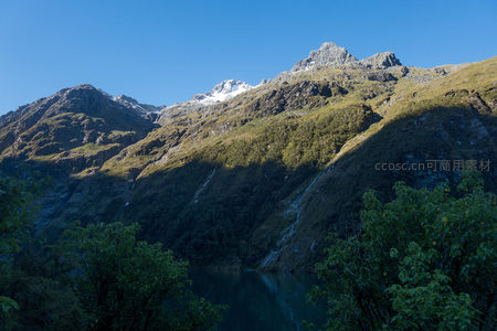 阳光穿透山谷洒落山脊，溪流垂挂绿坡映湖光