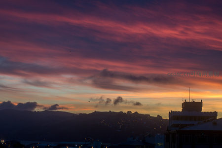 城市黄昏航拍：层叠彩霞映照山峦与楼宇剪影