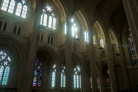 仰视教堂穹顶：光束穿窗照亮拱券与彩绘玻璃