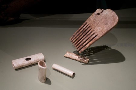 古代骨制梳子与管状饰件微距特写，展现精细雕刻工艺与岁月痕迹