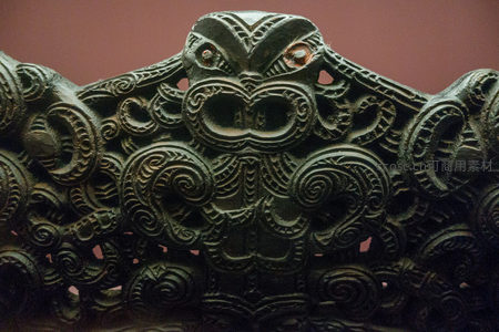 毛利族图腾面具式雕刻特写，夸张五官与螺旋纹构成神圣守护形象