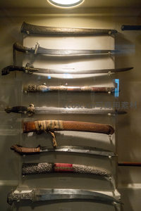 玻璃展柜中陈列的七把传统装饰性弯刀与剑鞘