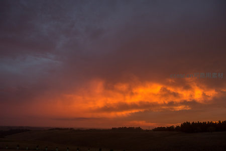 暮色中层积云迸发金红光芒，大地沉入深蓝阴影的戏剧性天际