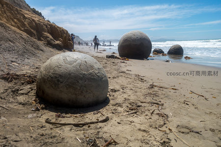 游客漫步莫埃拉基海滩，巨型圆石与碧海蓝天相映成趣