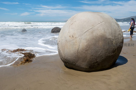 晴空下摩拉基巨石巍然屹立，海浪翻涌映衬其古老神秘气质
