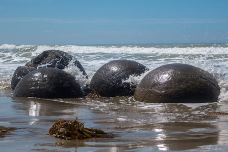海浪冲击摩拉基巨石群，水花四溅映射日光，质感粗粝而壮观