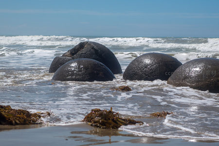 潮水退去后摩拉基巨石静卧浅滩，波纹轻抚岩体，宁静致远