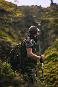 徒步者驻足山径回望，背包手杖相伴绿谷幽深景致