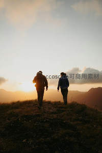 情侣携手行于山脊小径，夕阳余晖映照远山云海