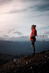红衣旅人屹立火山岩顶，远眺层叠雪岭与辽阔山谷