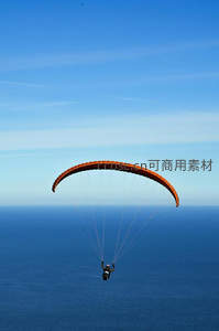 橙色滑翔伞翱翔碧海蓝天之上，自由飞行的极致体验