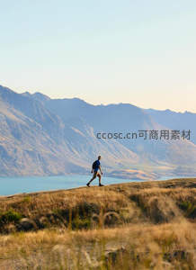 湖畔山脊上独行者缓步前行，远山如黛映衬碧水清波