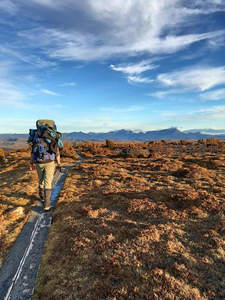 极地苔原小径上负重徒步者远行，远山与流云相映