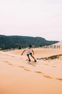 沙丘滑板少年驰骋金黄沙海，远山苍翠映衬动感瞬间
