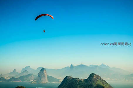 橙色滑翔伞掠过里约热内卢糖面包山，城市与自然交融