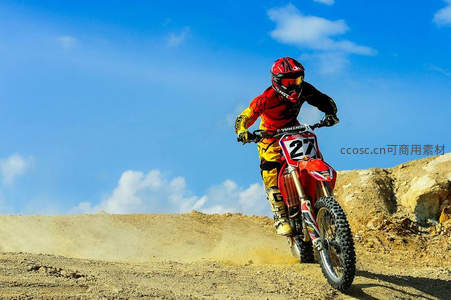 越野摩托手腾跃沙丘扬尘，红黄战衣映衬湛蓝晴空