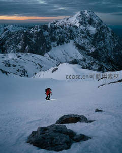 雪夜登山者头灯照亮雪径，孤影前行于巍峨雪山之巅