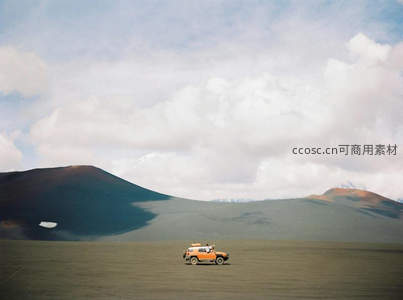 橙色越野车驰骋高原荒漠，远山雪峰映衬辽阔天地