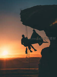 日落悬崖吊床剪影，探险者静享壮丽山河余晖