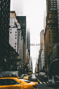 雾霭中的纽约街景，黄色出租车穿行于摩天大楼峡谷之间