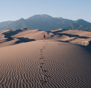 孤独旅人踏沙而行，连绵沙丘与远山构成壮阔自然画卷
