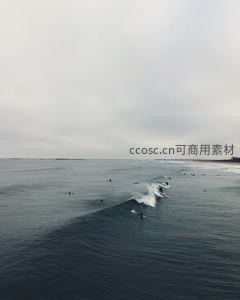 航拍海浪涌动冲浪者群聚，灰云下深蓝海域活力四射