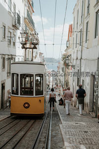 里斯本黄色电车穿行老城窄巷，行人漫步石板路
