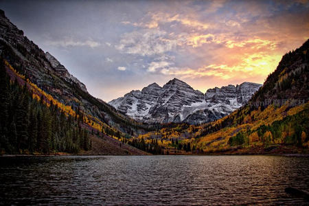 秋日马龙山湖畔层林尽染，雪峰倒映水面如画般静谧壮丽