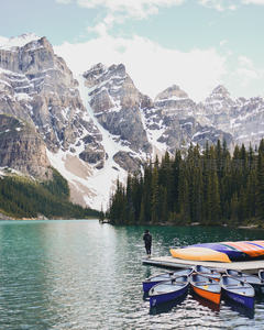 雪山湖泊畔独行者与彩色皮划艇静谧停泊