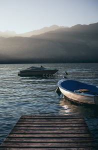 晨光中的湖面小艇与木码头，远山朦胧光影柔和