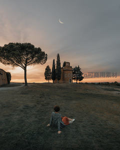 女子背坐草坡凝望夕阳下的乡村小教堂与新月