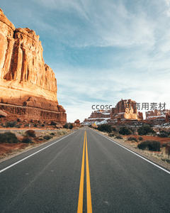 峡谷间笔直公路穿行红岩峭壁，远山覆雪映蓝天