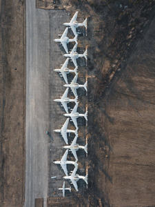 航拍废弃机场停机坪上整齐排列的退役客机群