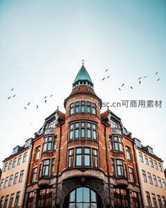 哥本哈根红砖转角建筑仰拍，飞鸟掠过青顶塔楼与澄澈天空