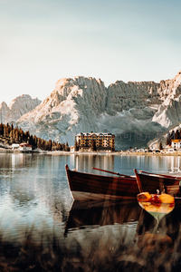 意大利多洛米蒂湖畔木舟静泊，背景雄伟岩壁与湖边建筑倒影如画