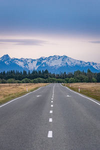 新西兰南岛空旷公路直通雪山，两侧草原树林延伸至天际线
