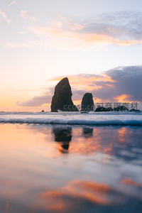 海蚀柱倒影于潮汐浅滩，晚霞浸染海岸线的梦幻时刻