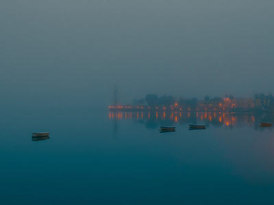 晨雾湖面孤舟点点，远岸灯火倒影如星