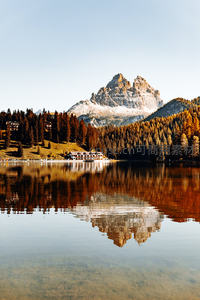 秋日湖畔雪山倒影如画，木屋隐于金松林间