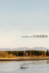白帆船泊于浅湾，远山层叠林带环绕，黄昏柔光洒满水面