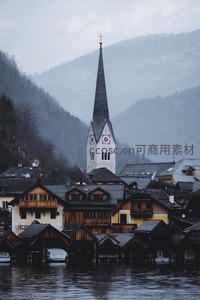 薄雾缭绕的湖边村落，高耸钟楼穿云而出，木屋错落水岸间