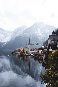 雾霭中的哈尔施塔特湖畔小镇，尖塔倒映水面，雪峰环抱静谧如诗