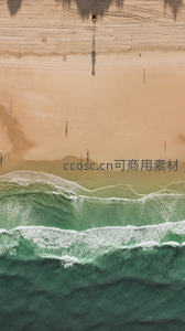 俯瞰海岸线：海浪轻抚金色沙滩与人影剪影