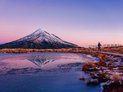 塔拉纳基山雪顶倒映冰湖，暮色中一人静观壮丽山景