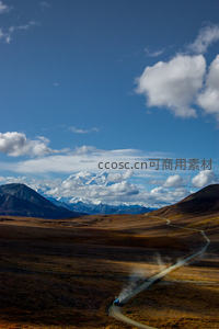 航拍阿拉斯加德纳里峰下蜿蜒土路与越野车扬尘行进