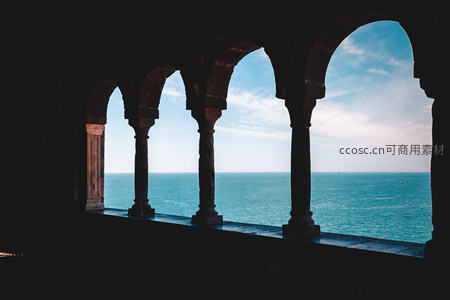 拱廊剪影下的蔚蓝海景，古典石柱与天光云影交织成诗