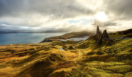 苏格兰斯托尔老人岩峰耸立，云破日出照亮苔原与海湾