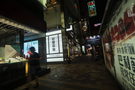 彩星中心夜巷：模糊人影穿梭于珠宝店与广告墙间的都市光影