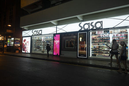 Sasa化妆品店夜景：明亮橱窗映照路人驻足选购的都市消费瞬间