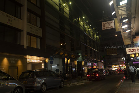 香港夜市街景，霓虹招牌闪烁，车流穿梭于狭窄街道间